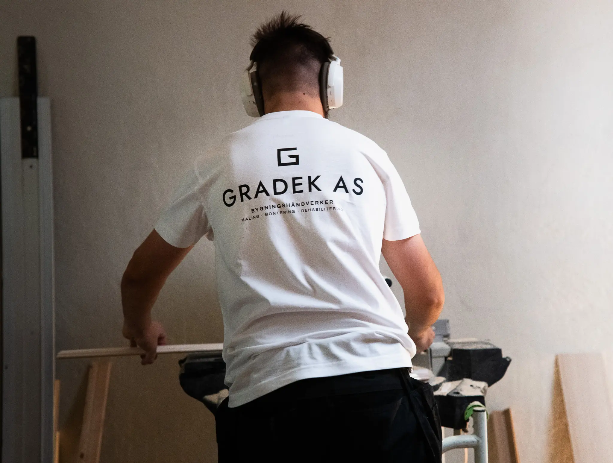 Snekker fra Gradek AS kapper en planke ved arbeidsbenken